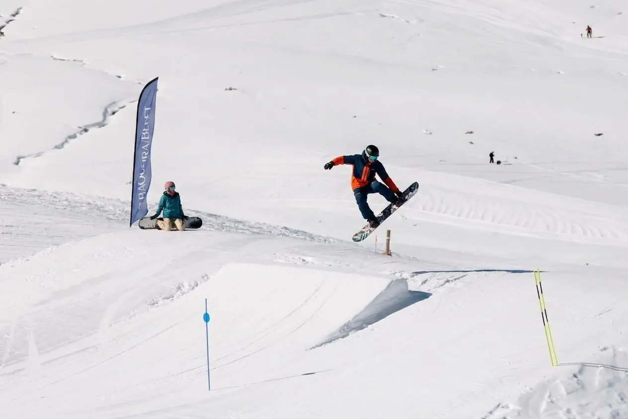 Rider de snowboard a saltar um módulo do snowpark Era Marmota em Baqueira Beret