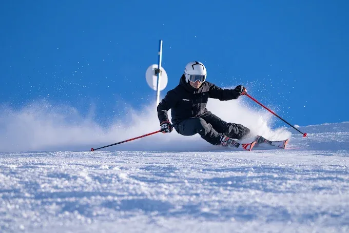 Skieur de niveau avancé en angulation maximale pendant un virage coupé à Baqueira Beret — Alpine Ski Academy
