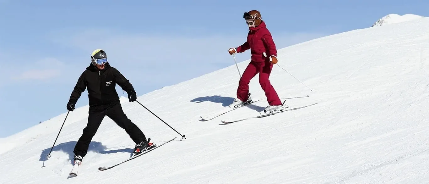 Instrutor de esqui a descer em cunha à frente de uma aluna jovem, nível A-B, em Baqueira Beret — Alpine Ski Academy