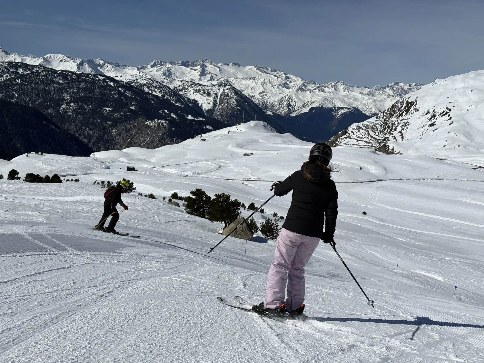 Dos alumnos en una pendiente abierta de Baqueira Beret durante su clase de esquí, con el valle al fondo — Alpine Ski Academy