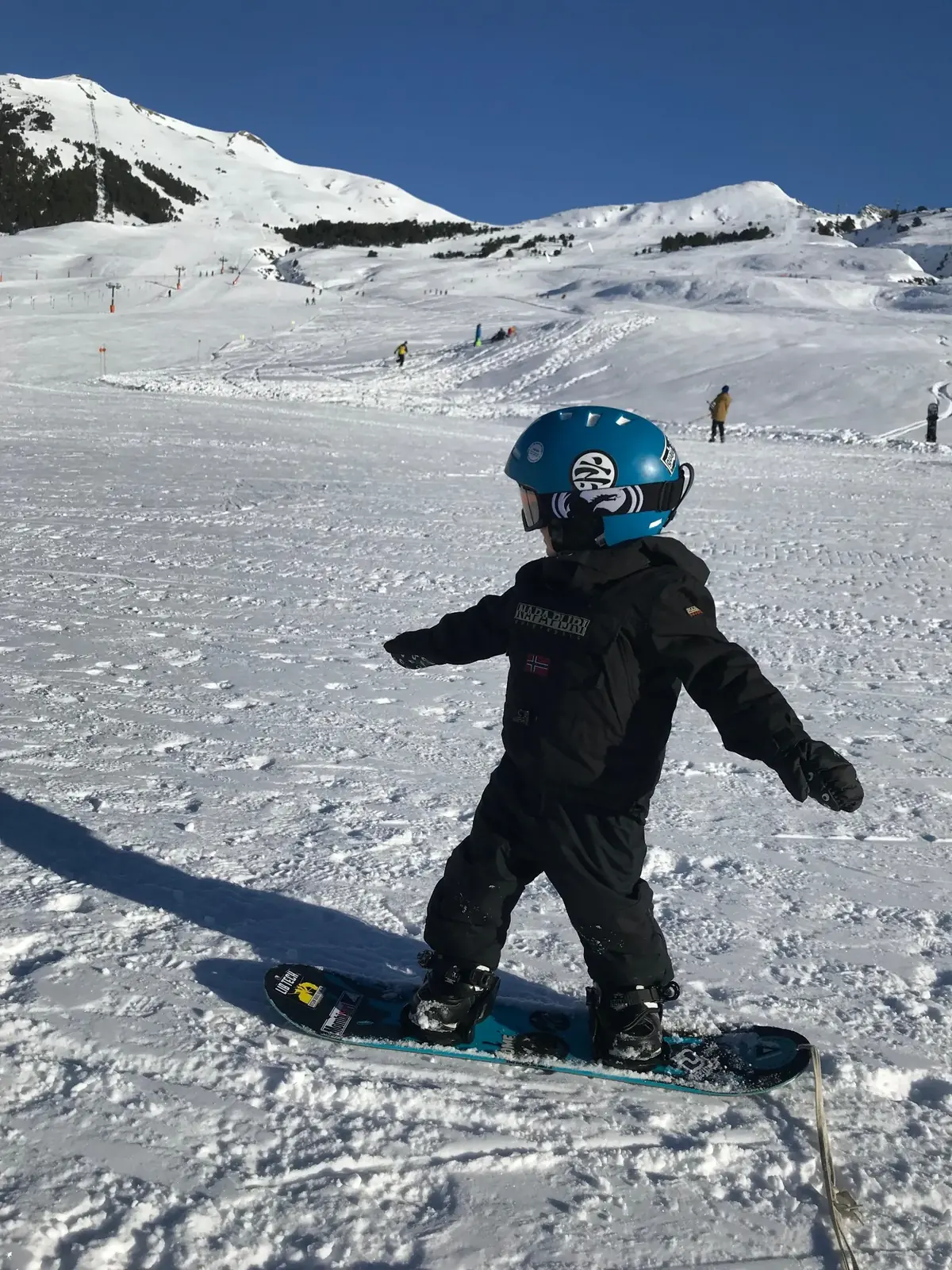 Enfant en cours de snowboard à Baqueira glissant sur la carre talons dans la zone débutants